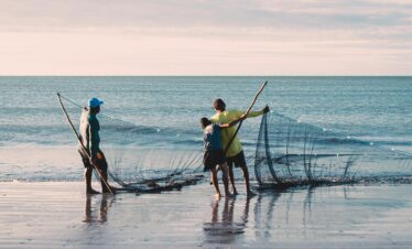 Fishermen with nets at João Pessoa beach in Brazil during sunset.