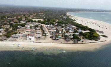 A stunning aerial shot of a coastal village in Lamu County, Kenya, featuring sandy beaches and clear ocean waters.