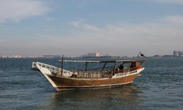A traditional wooden dhow sailing near the Doha skyline, Qatar.