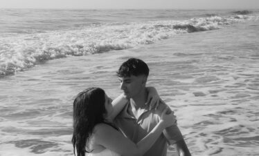 Monochrome scene of a couple embracing in the waves at the beach, evoking romance.