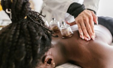 An adult woman receiving soothing cupping therapy by a professional masseuse in a calm spa setting.