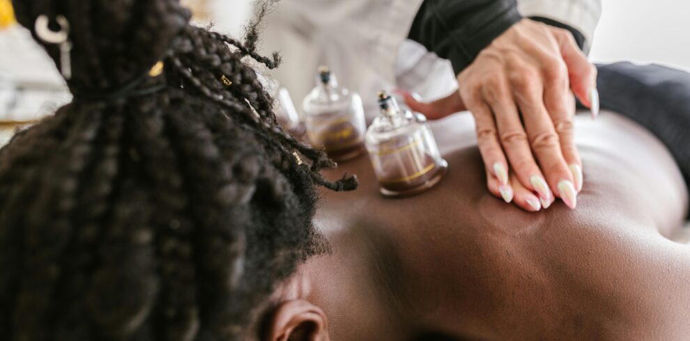 An adult woman receiving soothing cupping therapy by a professional masseuse in a calm spa setting.