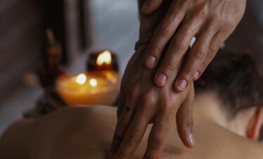 Close-up of a soothing back massage in a candlelit spa, promoting relaxation and wellness.