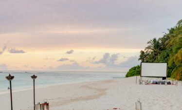 Beautiful and intimate beach setup with romantic decorations at sunset on a sandy shore.
