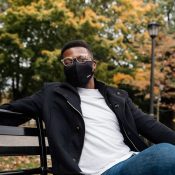 man in black jacket and blue denim jeans sitting on bench during daytime